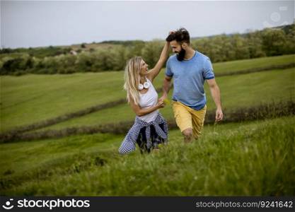 Loving young couple enjoying a walk through grass land on a summer day
