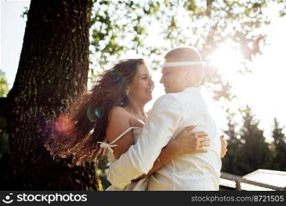 loving young couple having fun outdoors on summer sunny day. Man and woman are hugging near tree in park. valentines day.. loving young couple having fun outdoors on summer sunny day. Man and woman are hugging near tree in park. valentines day