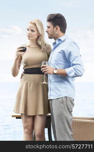 Loving young couple having red wine at outdoor restaurant by lake
