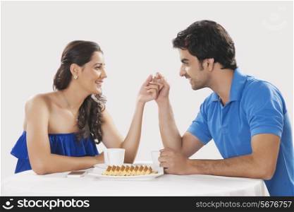 Loving young couple holding hands while having coffee over white background