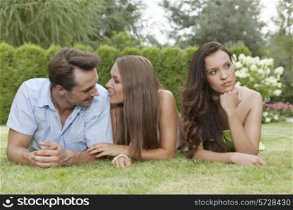 Loving young couple ignoring female friend in park