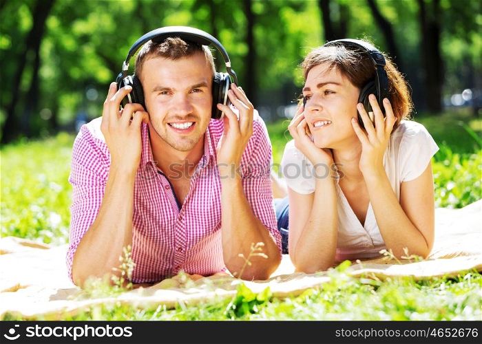 Loving young couple in summer park listening music. Weekend in park