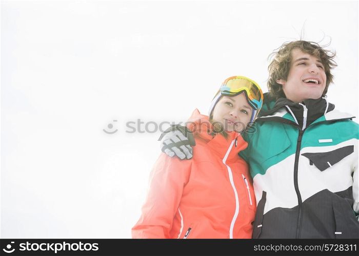 Loving young couple in warm clothing against clear sky
