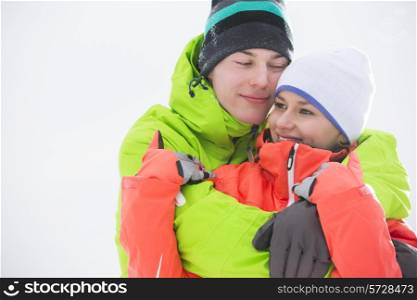Loving young couple in warm clothing embracing outdoors