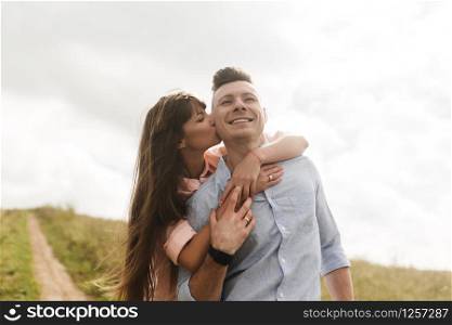 Loving young couple kissing and hugging in outdoors. Love and tenderness, dating, romance, family concept.. Loving young couple kissing and hugging in outdoors. Love and tenderness, dating, romance, family, anniversary concept.