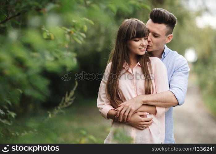 Loving young couple kissing and hugging in outdoors. Love and tenderness, dating, romance, family concept.. Loving young couple kissing and hugging in outdoors. Love and tenderness, dating, romance, family, anniversary concept.