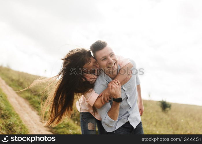 Loving young couple kissing and hugging in outdoors. Love and tenderness, dating, romance, family concept.. Loving young couple kissing and hugging in outdoors. Love and tenderness, dating, romance, family, anniversary concept.