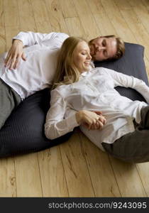 Loving young couple lying and kissing on the floor at home