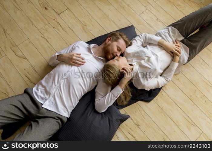 Loving young couple lying and kissing on the floor at home