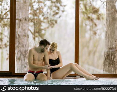 Loving young couple relaxing in the spa center by swimming pool