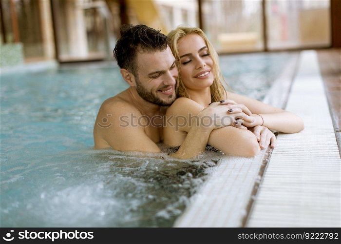 Loving young couple relaxing in the swimming pool at spa center