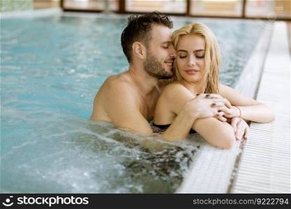 Loving young couple relaxing in the swimming pool at spa center