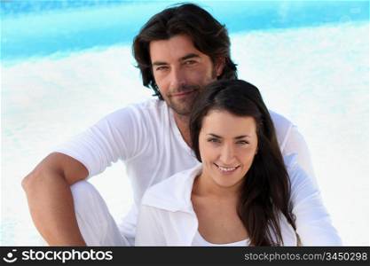 Loving young couple sitting by a pool
