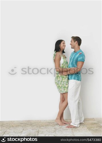 Loving young couple standing against wall