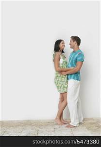 Loving young couple standing against wall