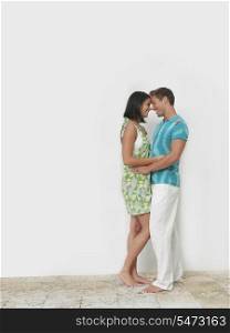 Loving young couple standing together against wall