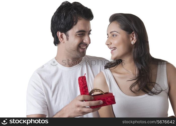 Loving young man gifting bangles to woman over white background