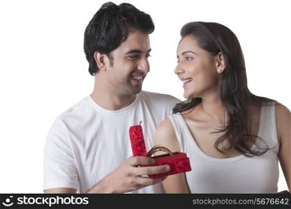 Loving young man gifting bangles to woman over white background