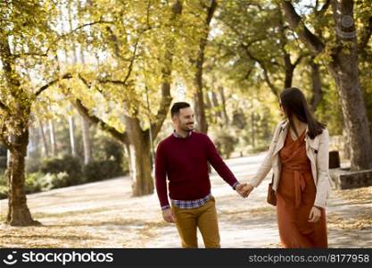 Loving young woman and man walking in city park holding hands