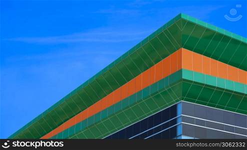 Low angle and side view of colorful rooftop of modern building against blue sky