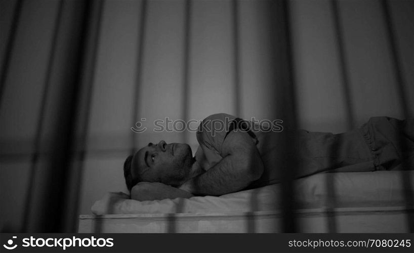 Low angle black and white scene of a criminal on his bed