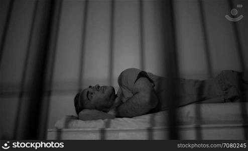 Low angle black and white scene of a criminal on his bed