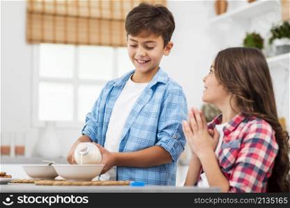 low angle brother pouring milk his sister