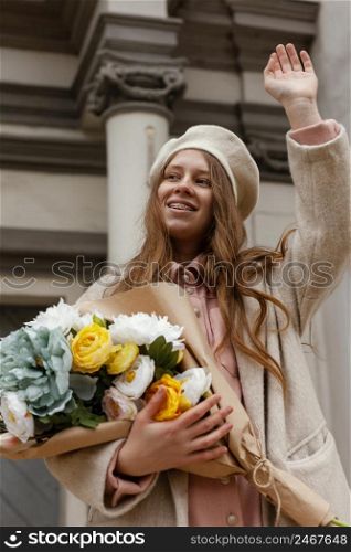 low angle elegant woman outdoors holding bouquet flowers spring