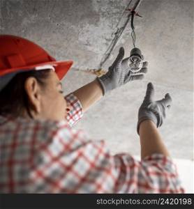 low angle female construction worker with light bulb