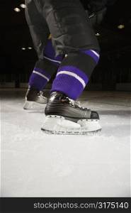 Low angle of hockey player&acute;s legs and skates on ice rink.