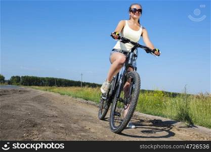 Low angle of young beautiful woman riding a bicycle in a park. Summer bike walk