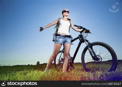 Low angle of young beautiful woman riding a bicycle in a park. Summer bike walk