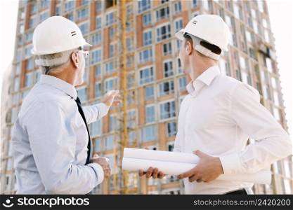 low angle people with helmets looking scaffolding design