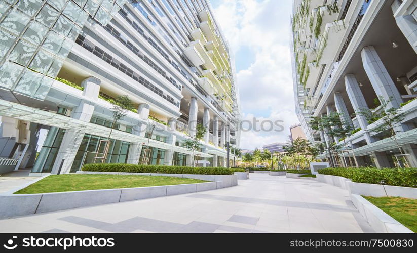 Low angle perspective view of empty pavement and modern office building with green eco concept balcony .