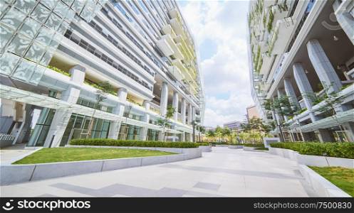 Low angle perspective view of empty pavement and modern office building with green eco concept balcony .