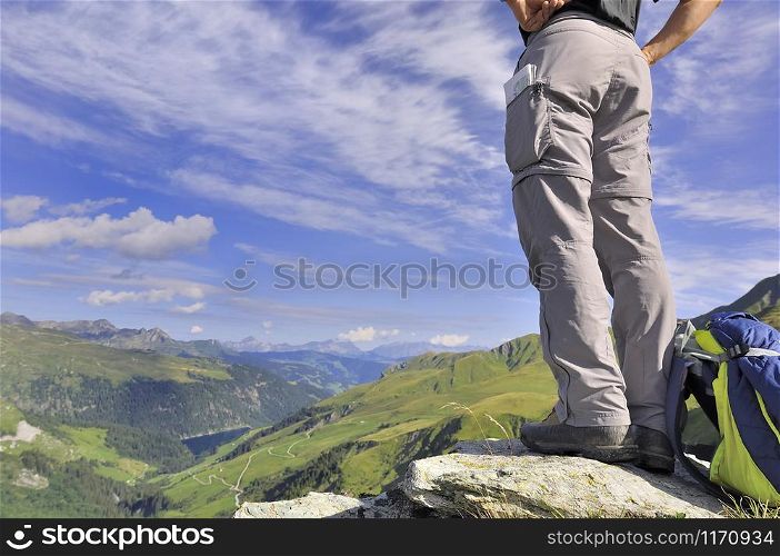 low-angle shot of a hiker standing at the top in beautiful alpine mountain in summer