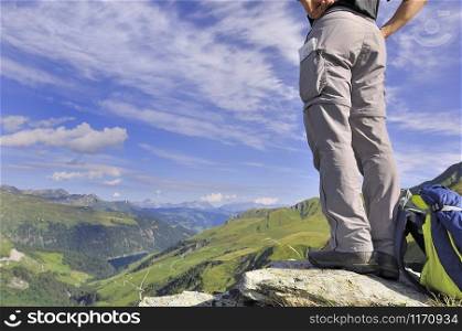 low-angle shot of a hiker standing at the top in beautiful alpine mountain in summer