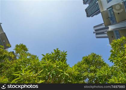 Low angle shot of modern buildings and green with clear sky background.