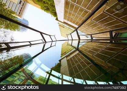 Low angle shot of modern glass buildings and green with clear sky background.