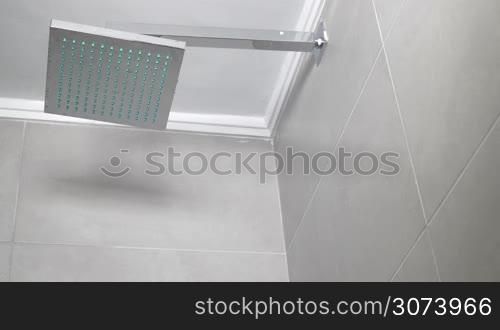 Low angle shot of turning on and off the shower, water pouring from big square showerhead