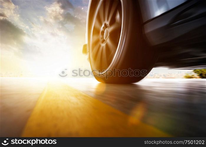 Low angle side view of car driving fast at sunset with motion speed effect .