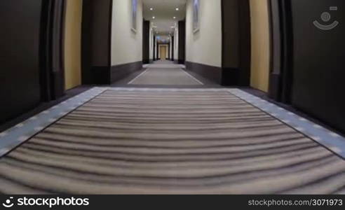 Low-angle steadicam shot of moving along the passageway in hotel.
