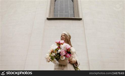 low angle stylish woman outdoors holding bouquet flowers spring