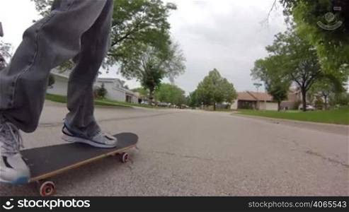 Low angle tracking shot, following a skater skateboarding down the street.