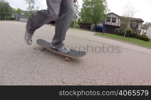 Low angle tracking shot, following a skater skateboarding down the street.