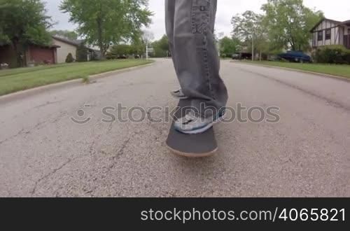 Low angle tracking shot, in front of a skater skateboarding down the street.