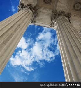 Low angle view looking up at blue sky with clouds and columns of Supreme Court building in Washington DC.