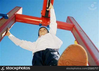 Low angle view of a boy on a jungle gym