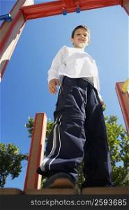 Low angle view of a boy smiling and standing on a jungle gym
