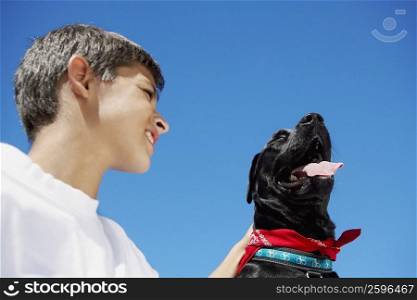 Low angle view of a boy smiling with a dog beside him